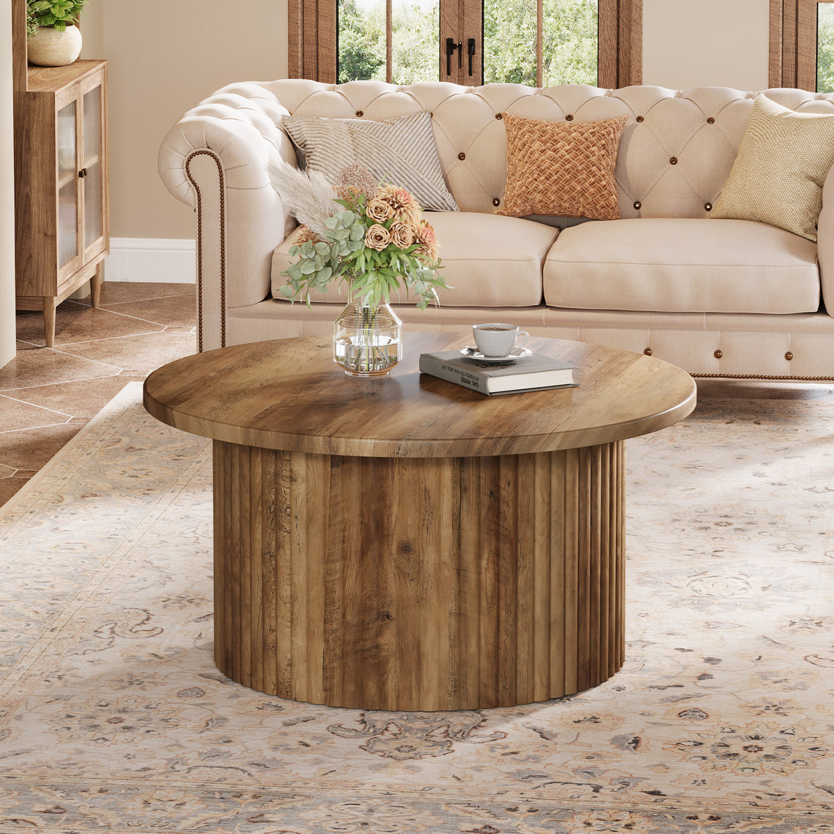 Table basse ronde en bois ton noyer devant un canapé capitonné