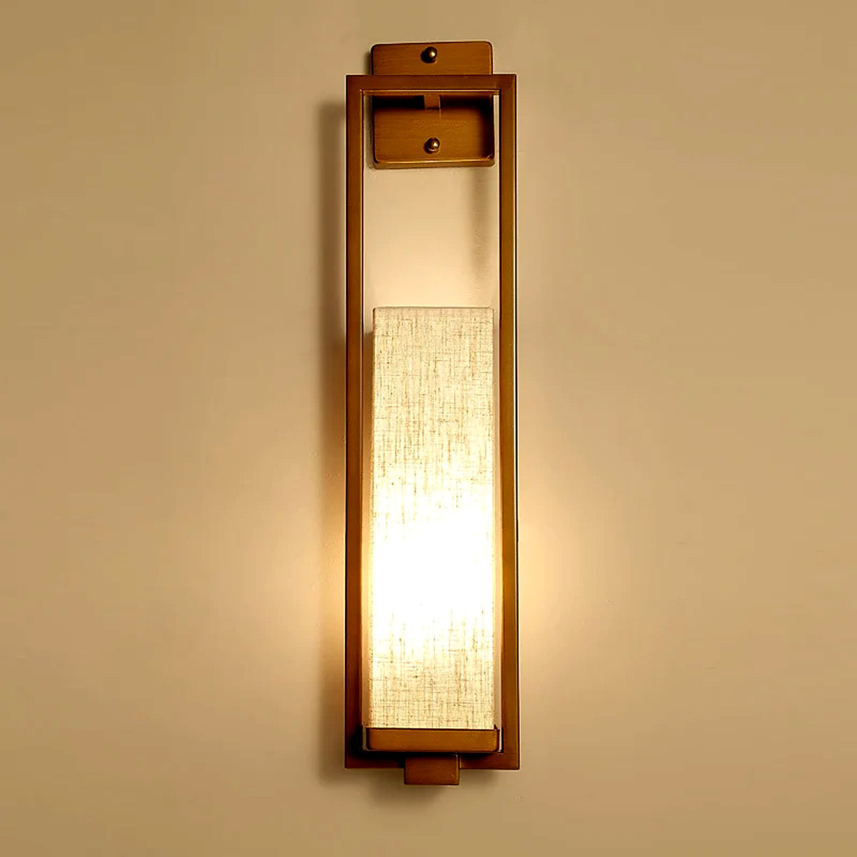 Détail de l'applique en lin et cadre bronze, lumière chaude