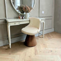 Fauteuil de coiffeuse pivotant crème et bois devant une coiffeuse