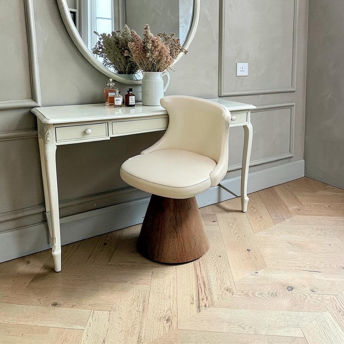 Fauteuil de coiffeuse pivotant crème et bois devant une coiffeuse