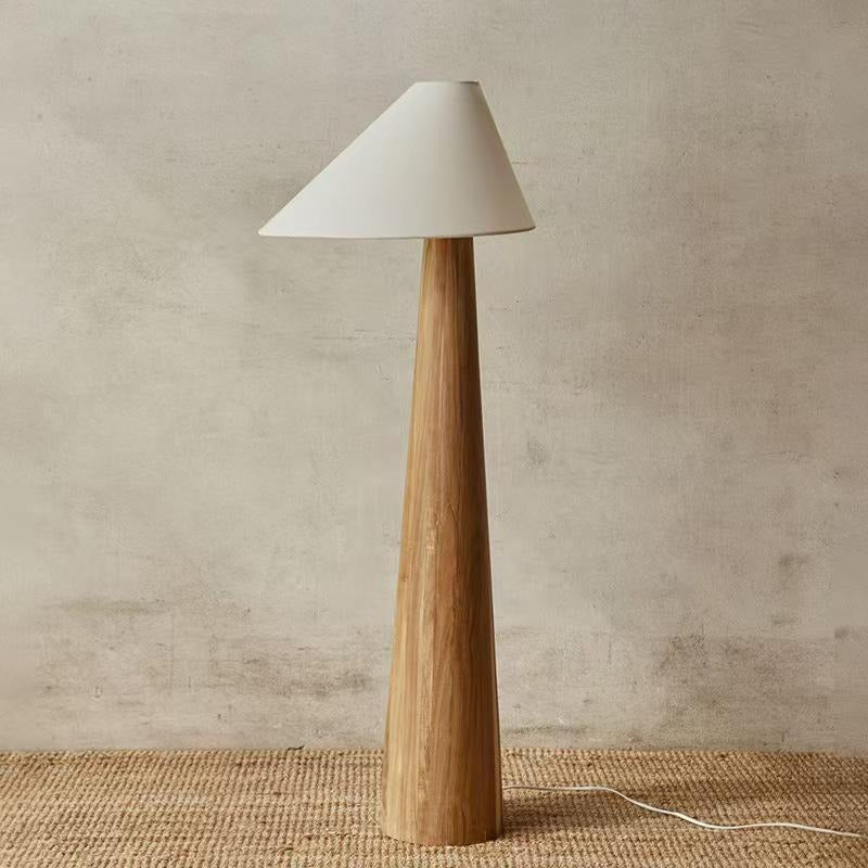 Lampadaire conique en bois massif devant un mur enduit