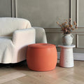 Pouf rond terracotta près d'un canapé bouclette