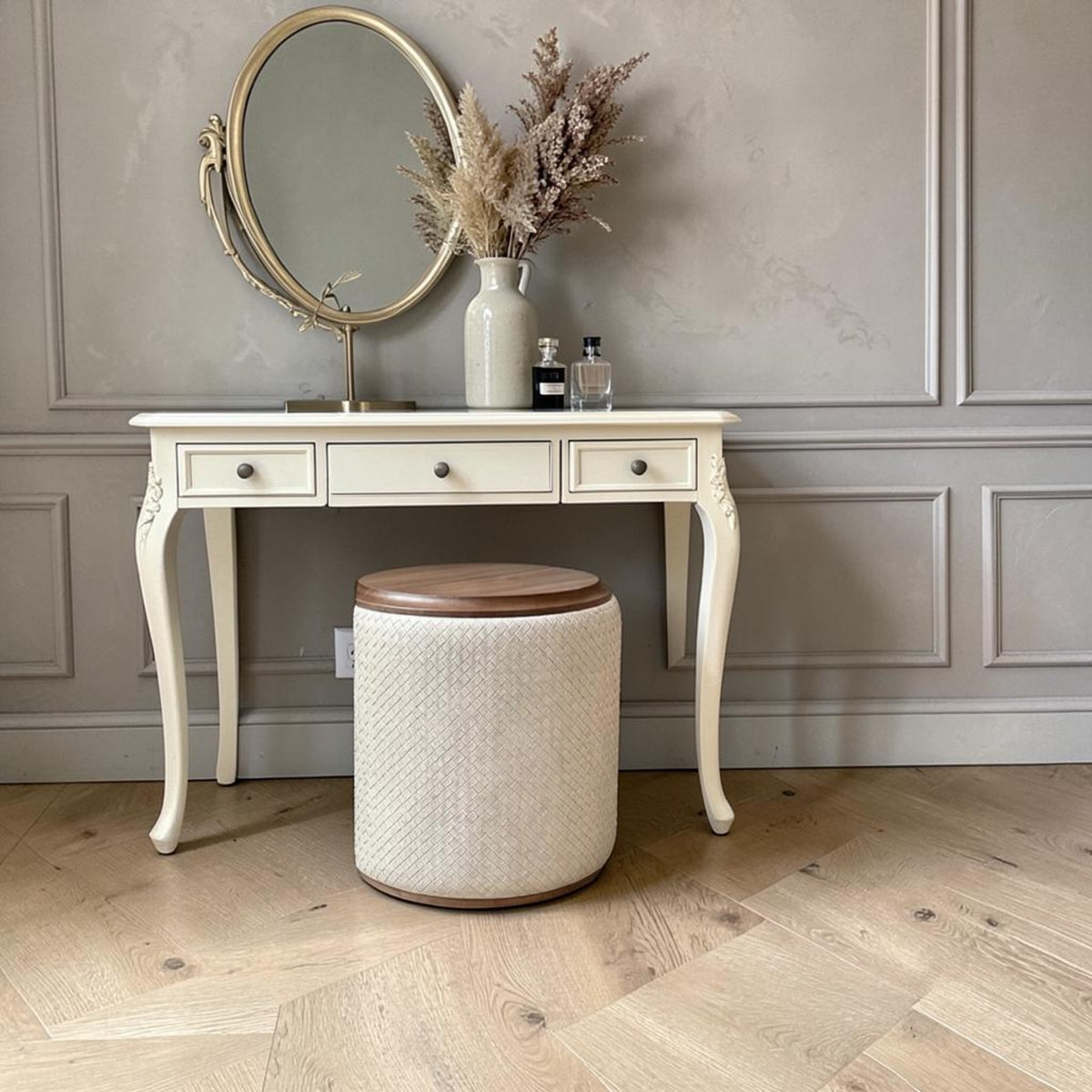 Tabouret rond tressé abricot devant une coiffeuse crème