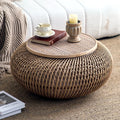 Table basse ronde en rotin tressé AUBRYNE dans un salon, devant un canapé crème