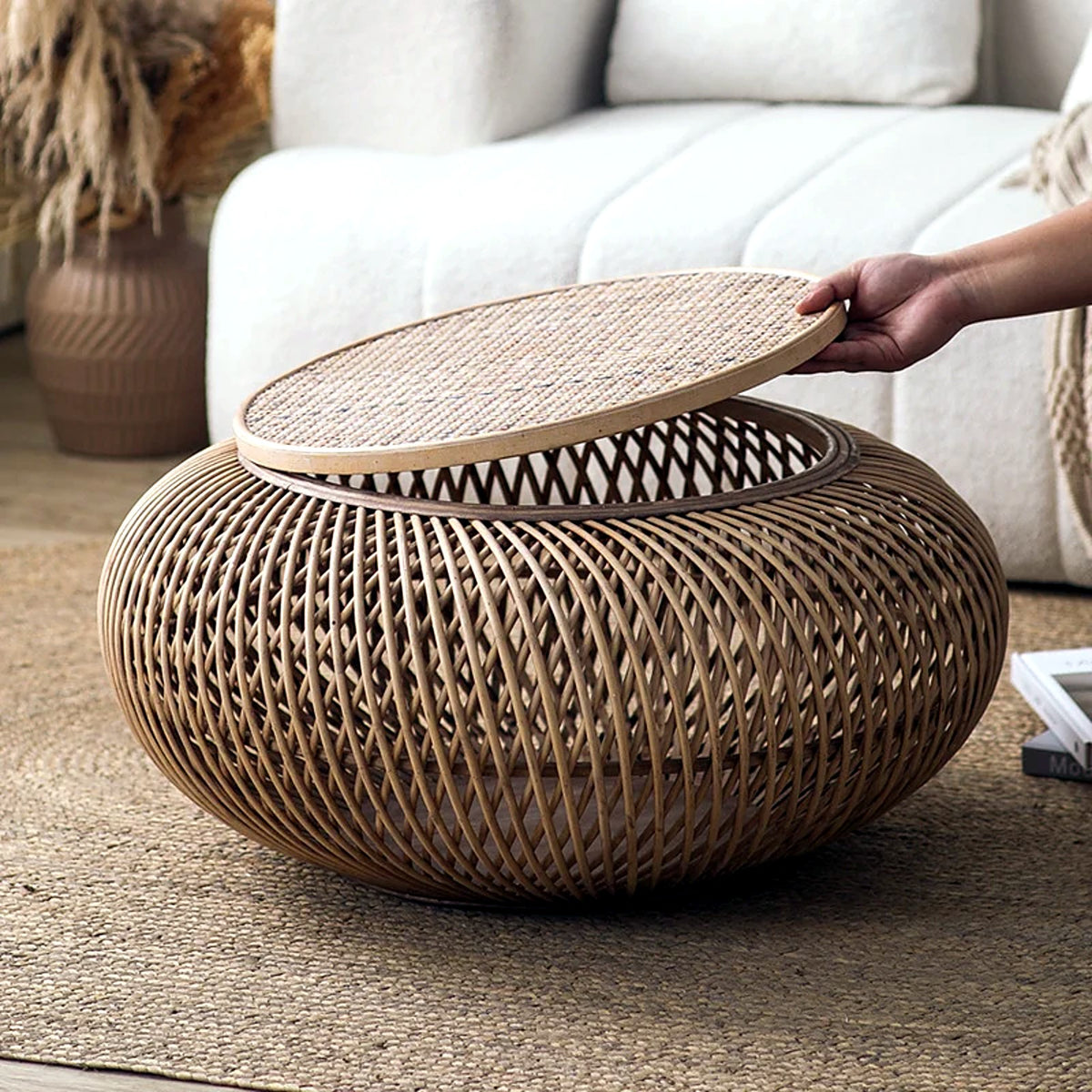 Plateau en cannage soulevé révélant le rangement caché de la table basse